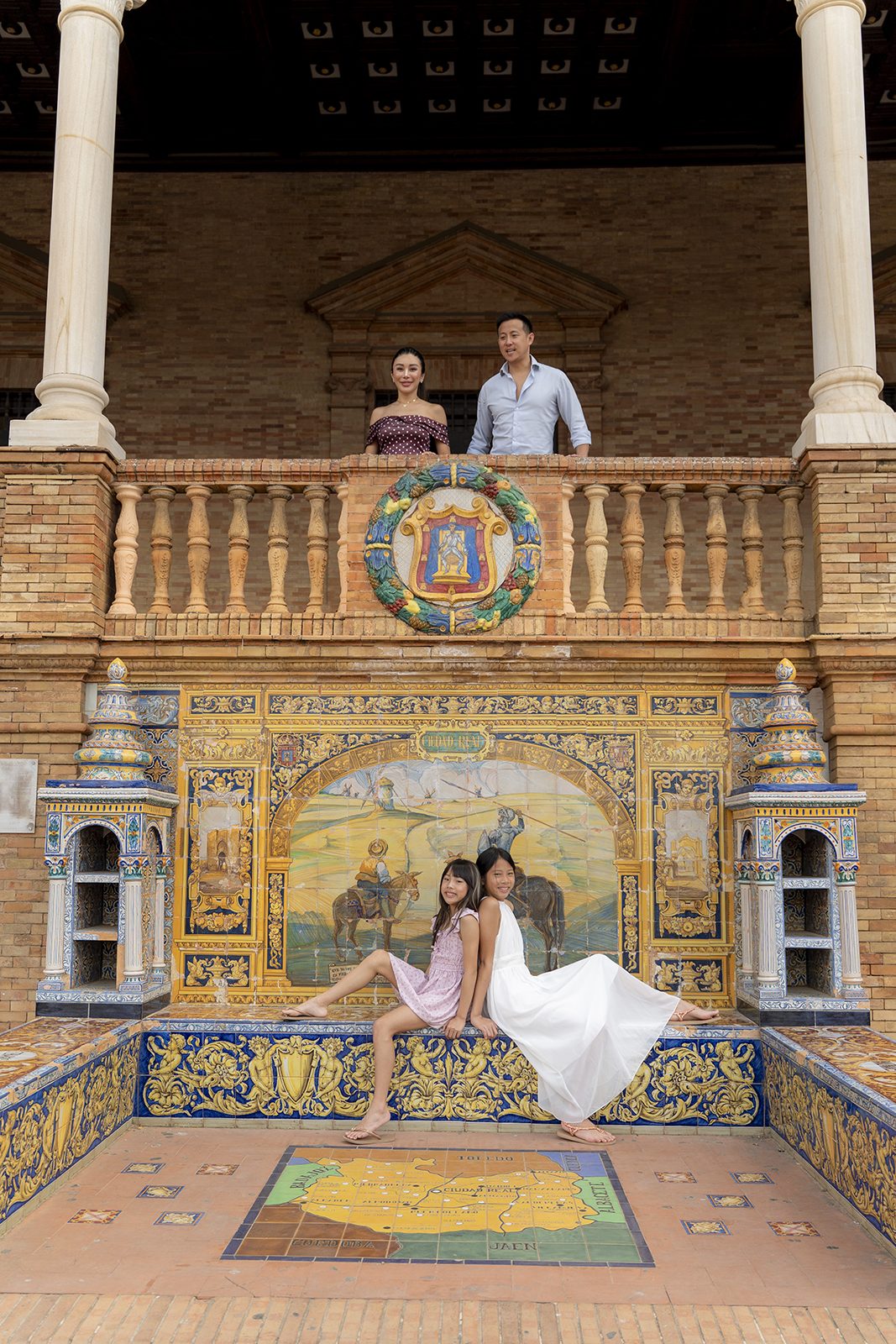 Parents on the balcony and daughters on the tiled steps at Plaza de España, Seville