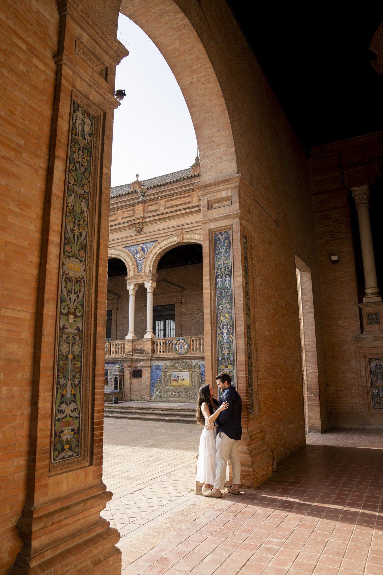 Couple framed by the brick arches of Plaza de España, Seville