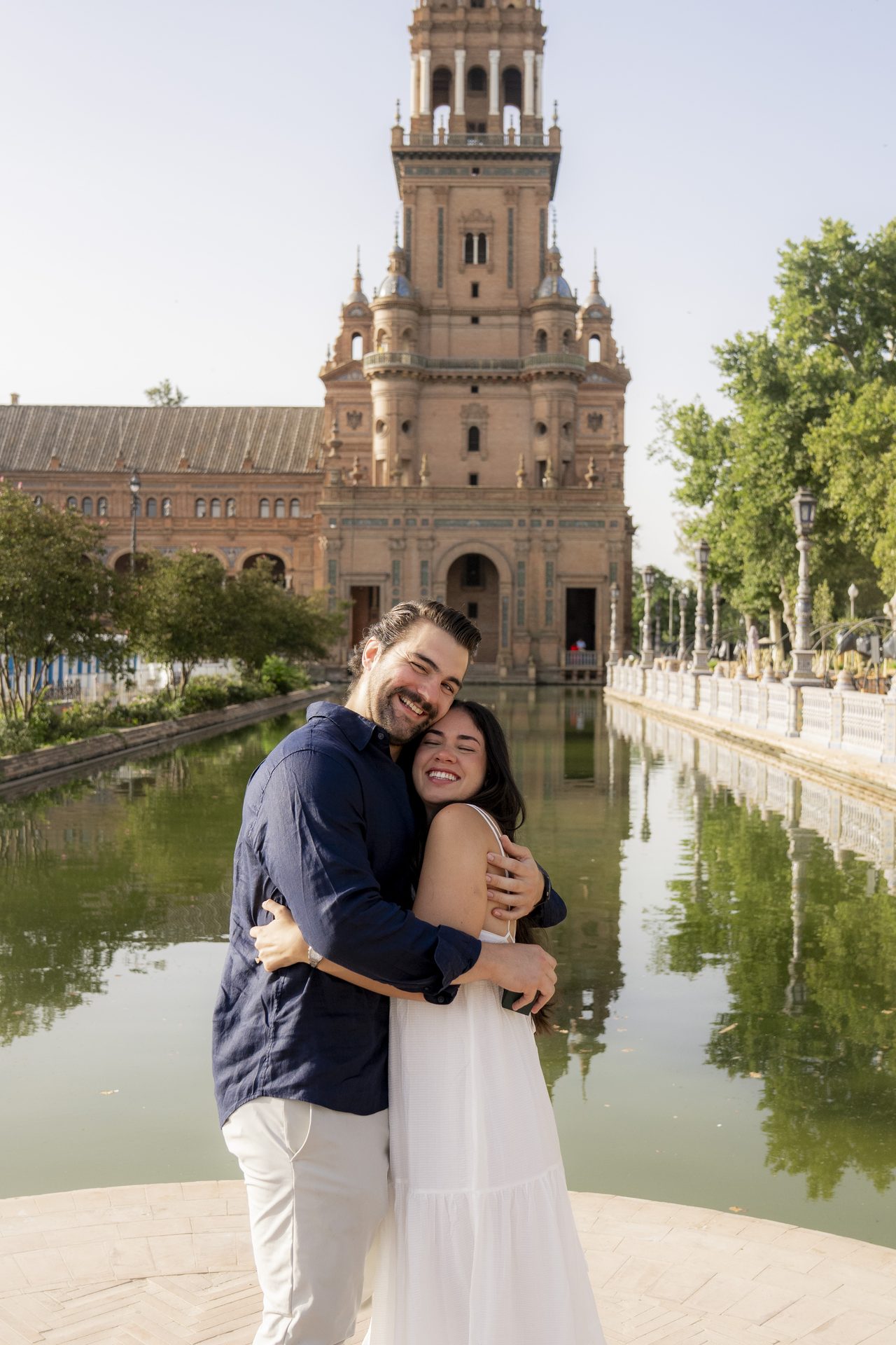 Newly engaged couple embracing by the canal at Plaza de España, Seville